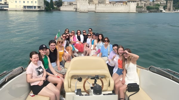 Un grupo de jóvenes mujeres está sentada en un bote en el agua frente al horizonte histórico de Mount Saint Michael.