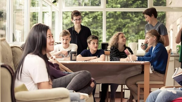 Un grupo de estudiantes se sienta en una mesa en la habitación luminosa del campus de Mount St. Mary's College.