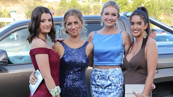 Cuatro estudiantes de la Mountain Creek State High School posan juntas frente a un auto con un paisaje verde de fondo.