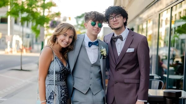 Tres estudiantes de la Mountainview High School están juntos en una calle de la ciudad con áreas verdes y edificios de fondo.