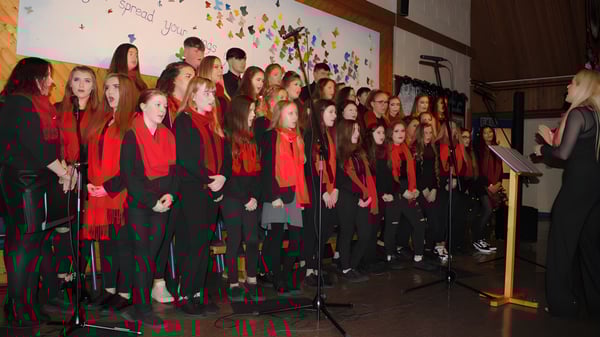 Un grupo de estudiantes se encuentra frente a un colorido mural en el campus del Moyne College.