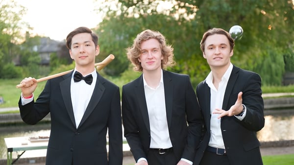 Tres jóvenes están en un área parecida a un parque en el campus de la escuela MPW Cambridge.