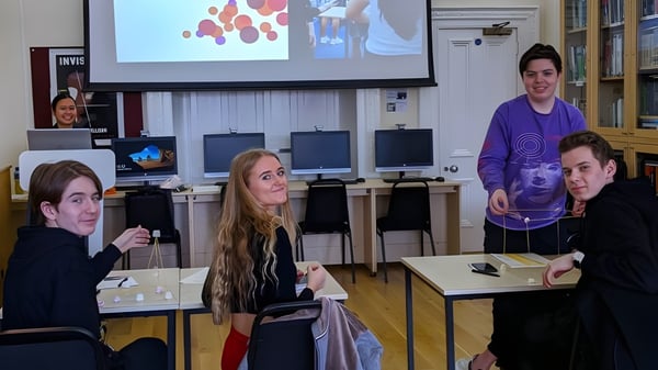 Estudiantes de la MPW London observan un gráfico colorido en una pantalla de proyección en el aula.