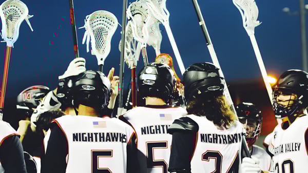 Un grupo de jugadores de lacrosse de la Murietta Valley High School lleva camisetas blancas con la inscripción NIGHTHAWKS en la espalda.