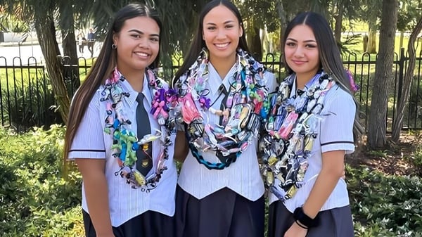 Tres estudiantes en uniformes escolares están juntas en un área verde en el campus del Murrumba State Secondary College.