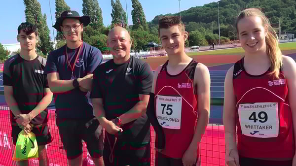 Un grupo de atletas está en la pista del Myddelton College frente a árboles y edificios.