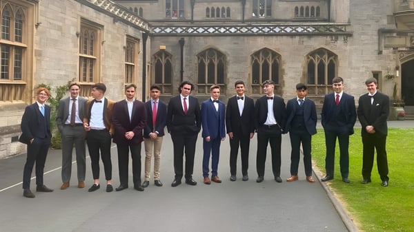 Un grupo de hombres en ropa formal está frente al edificio principal gótico del Myddelton College.