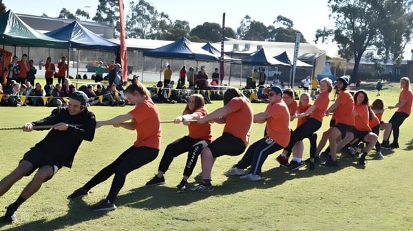 Un grupo de estudiantes del Nagle Community College participa en una actividad al aire libre con carpas de fondo.