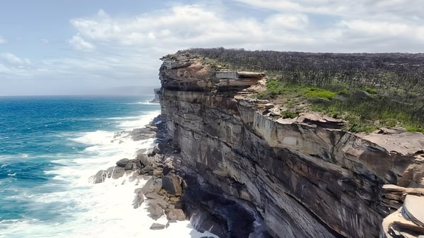 Un tramo rocoso de acantilado con vegetación exuberante da al mar turquesa en Nambour State College.