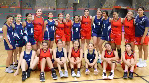 Un grupo de jóvenes jugadoras de baloncesto de la Napier Girls' High School posan juntas en la cancha de baloncesto.