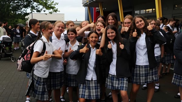 Un grupo de alumnas de la Napier Girls' High School posan en una acera y muestran el pulgar hacia arriba.