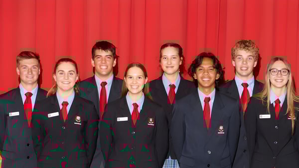 Un grupo de estudiantes de la Naracoorte High School está frente a una cortina roja en uniforme escolar.