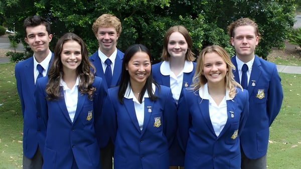 Un grupo de estudiantes de la Narrabeen Sports High School está junto en un prado con árboles al fondo.