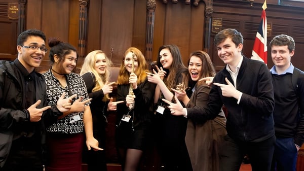 Un grupo de estudiantes está en el National Mathematics and Science College frente a revestimientos de madera históricos.