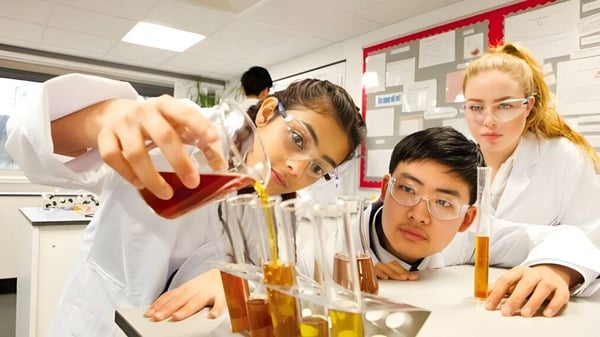 Tres estudiantes del National Mathematics & Science College trabajan juntos en un laboratorio en experimentos científicos.
