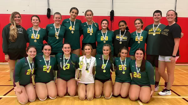 Un grupo de atletas femeninas de la Nativity BVM High School posan con medallas en el gimnasio.