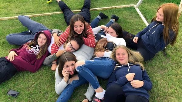 Un grupo de alumnas de la Nechako Valley Secondary School está tumbado en el césped y se abraza al aire libre.