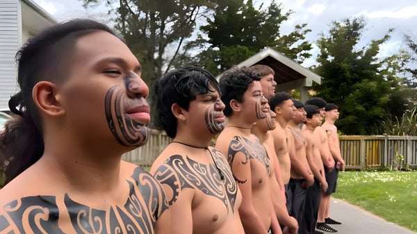 Un grupo de alumnos tatuados está en un prado frente a una construcción de madera en el terreno del Nelson College for Boys.
