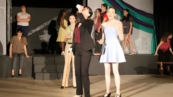 Un grupo de estudiantes de la New Garden Friends School está vestido formalmente en un escenario frente a una cortina.