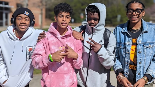 Cuatro estudiantes están juntos afuera en el campus de la New Garden Friends School.