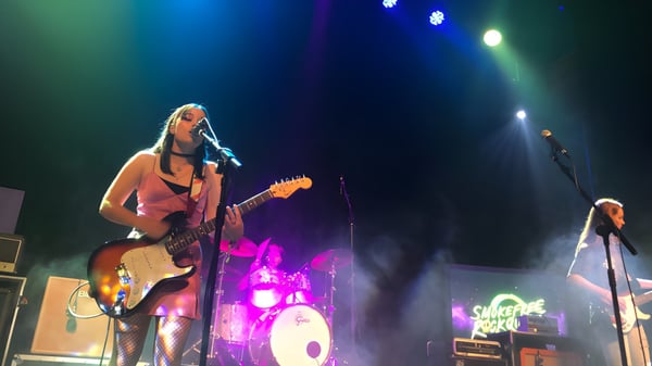 Una alumna de la New Plymouth Girls’ High School toca la guitarra eléctrica en el escenario con batería y amplificadores al fondo.