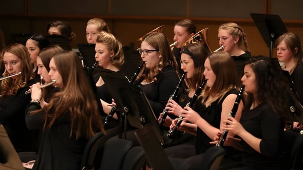 Un grupo de jóvenes músicos de la New Sarepta Community High School toca diferentes instrumentos como flautas y violines en el escenario.