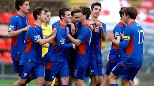 Estudiantes de la Newcastle High School están juntos en el campo de fútbol con camisetas azules.