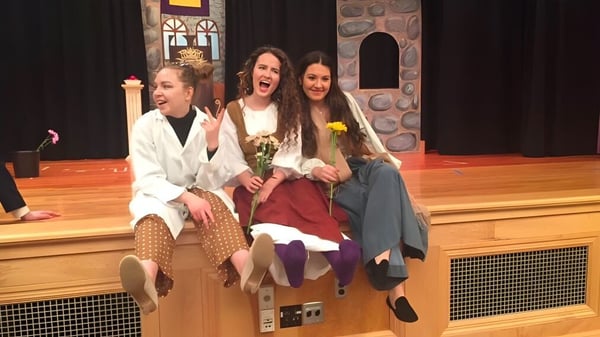 Tres estudiantes en trajes coloridos están en el escenario del Newcomb Central School District.