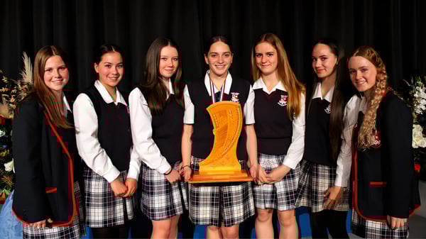 Estudiantes del Newlands College están juntos sosteniendo un trofeo.