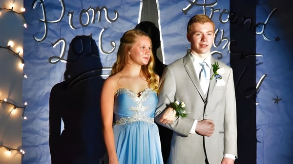 Una joven pareja está frente a la decoración con la inscripción Prom 2022 en el campus de la Newmarket High School.