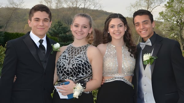 Cuatro estudiantes de la Newtown School están juntos afuera frente a un fondo de bosque verde.