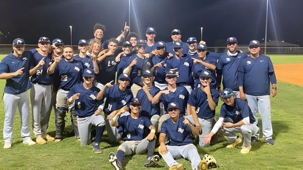 Estudiantes de la North Broward Preparatory School celebran por la noche en el campo de béisbol su victoria.