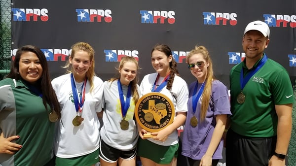Grupo de estudiantes de la North Central Texas Academy con medallas posando frente a un fondo con el logo de PRS.