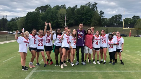 Un grupo de jóvenes deportistas entrena en el campo deportivo de la North Cross School bajo un cielo nublado.