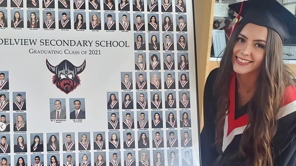 Un grupo de graduadas y graduados de la North Delta Secondary School del año 2021 con una joven en primer plano vestida con ropa de graduación.