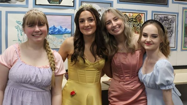 Cuatro estudiantes de la North Halifax Grammar School están frente a una pared con varias obras de arte enmarcadas.
