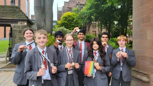 Un grupo de estudiantes en uniformes escolares está frente a un edificio histórico en el campus de la North Halifax Grammar School.