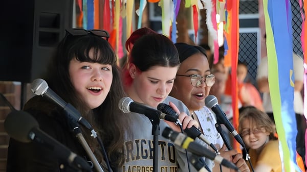 Tres alumnas están de pie frente a un fondo colorido en el campus de North Lake Senior Campus.
