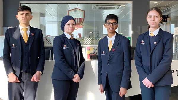 Cuatro alumnas y alumnos de la North London Grammar School están en el pasillo de la escuela.