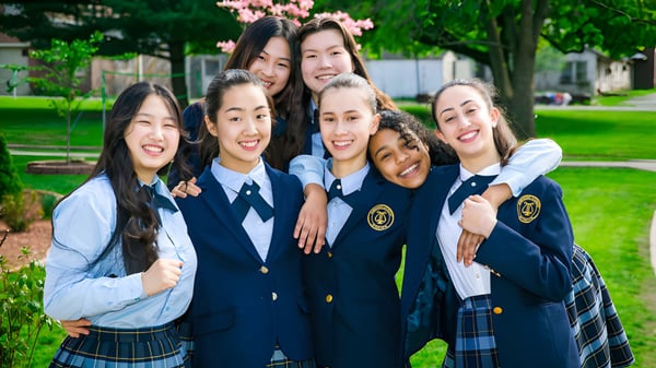 Un grupo de alumnas de la Northern Academy está al aire libre frente a cerezos en flor.