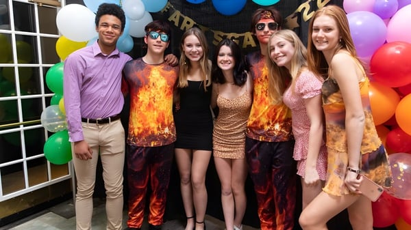 Estudiantes de la Northfield Mount Hermon School posan juntos frente a decoraciones festivas con globos.