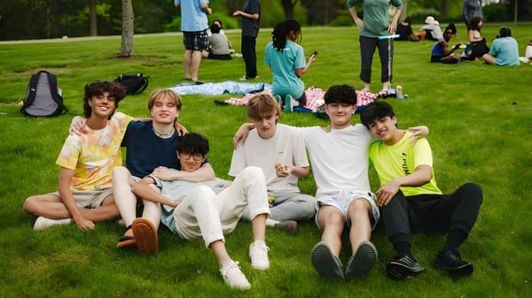 Un grupo de estudiantes de la Northfield Mount Hermon School se sienta juntos en un campo con árboles de fondo.
