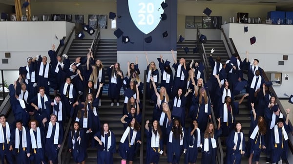 Un grupo de estudiantes de la Northpoint Christian School se reúne en una escalera con ropa de graduación para celebrar la exitosa finalización de la escuela.