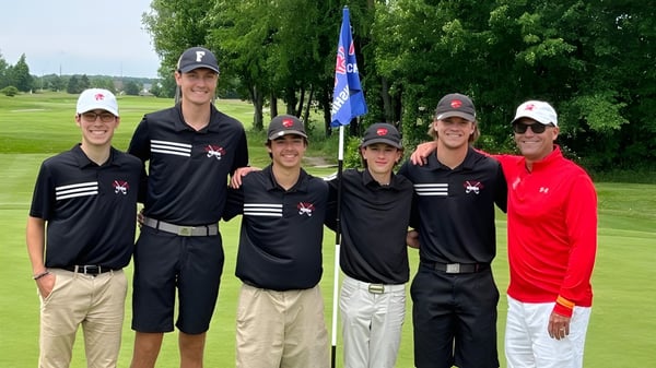 Un grupo de estudiantes de la Northview High School está junto en el campo de golf rodeados de árboles verdes.