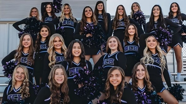 Un grupo de animadoras en uniformes uniformes posa frente a un cobertizo de metal en el campus de la Northwest Christian High School.