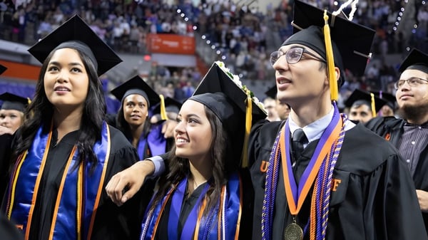 Un grupo de graduados de la Notre Dame High School está reunido en vestimenta de gala celebrando su graduación.