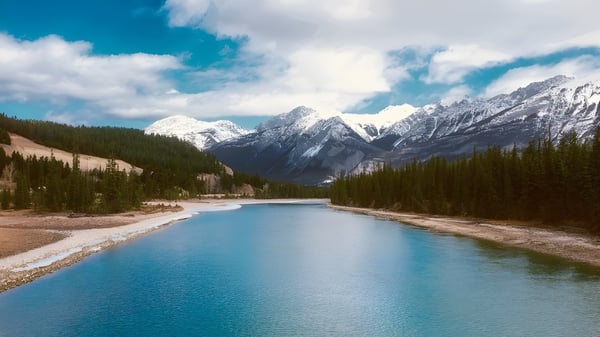 Un río tranquilo fluye a través de un paisaje montañoso con picos nevados cerca de la Notre Dame High School en Calgary.