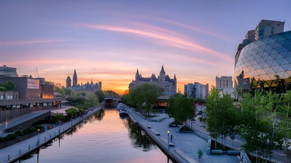 Una tranquila vista urbana con un canal en primer plano cerca de la Notre Dame High School al atardecer.
