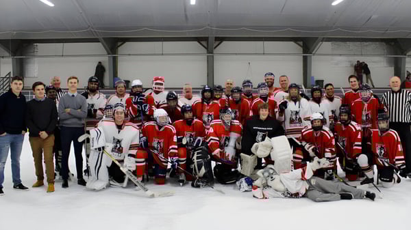 Un grupo de estudiantes de la Nottawasaga Pines Secondary School está en sus uniformes de hockey sobre la pista de hielo de un pabellón.