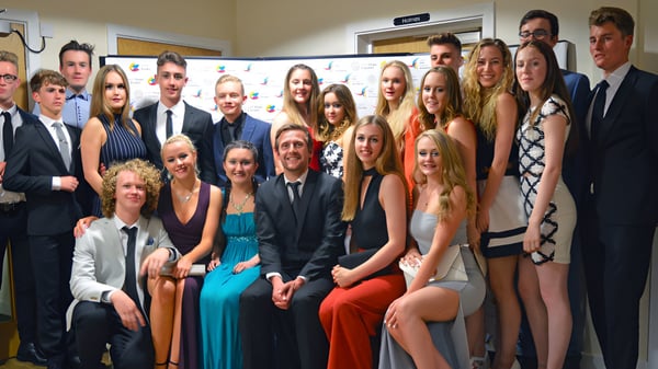 Un grupo de estudiantes del Oak Leaf Studio posan juntos frente a un edificio escolar.